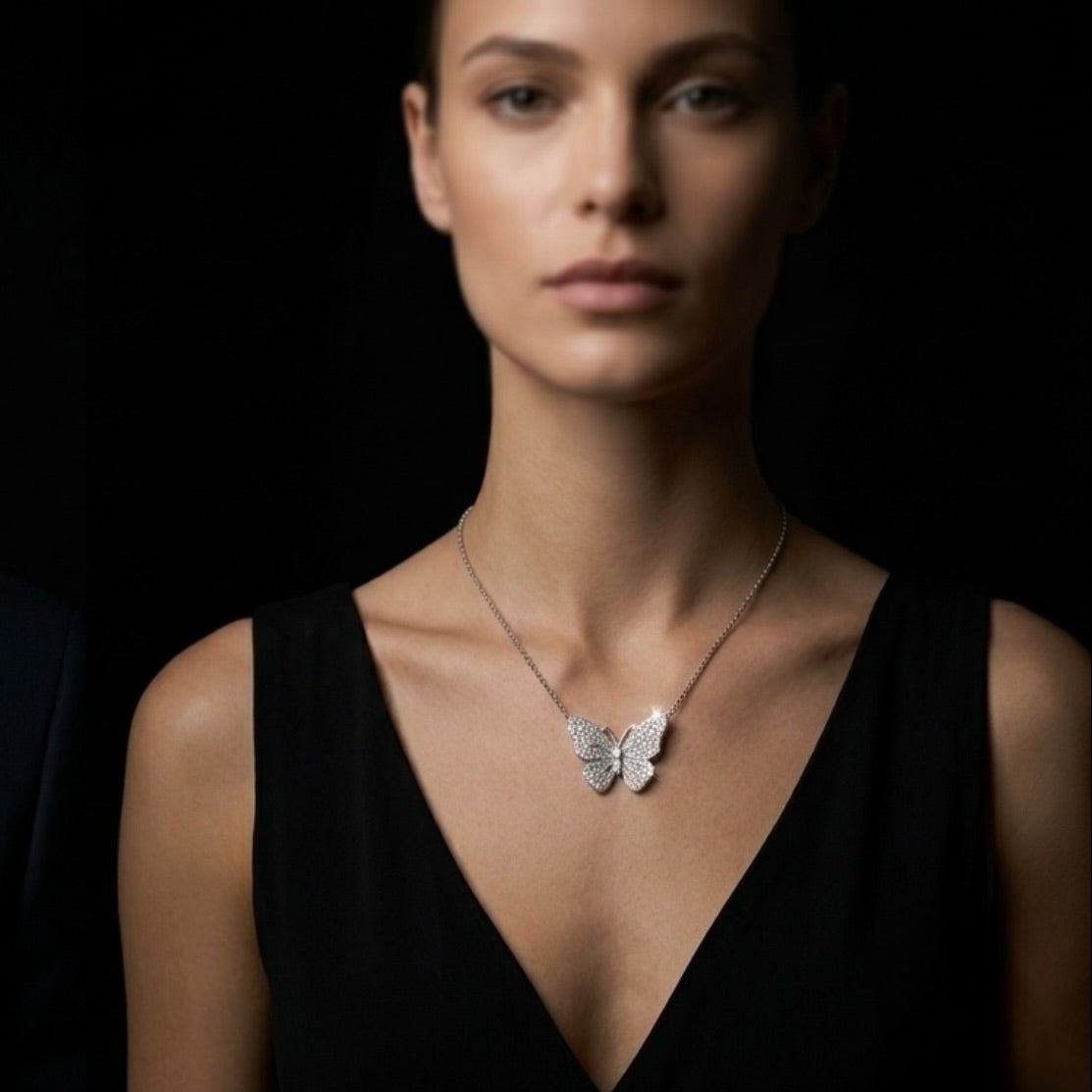 Man and woman wearing butterfly necklaces against a black background