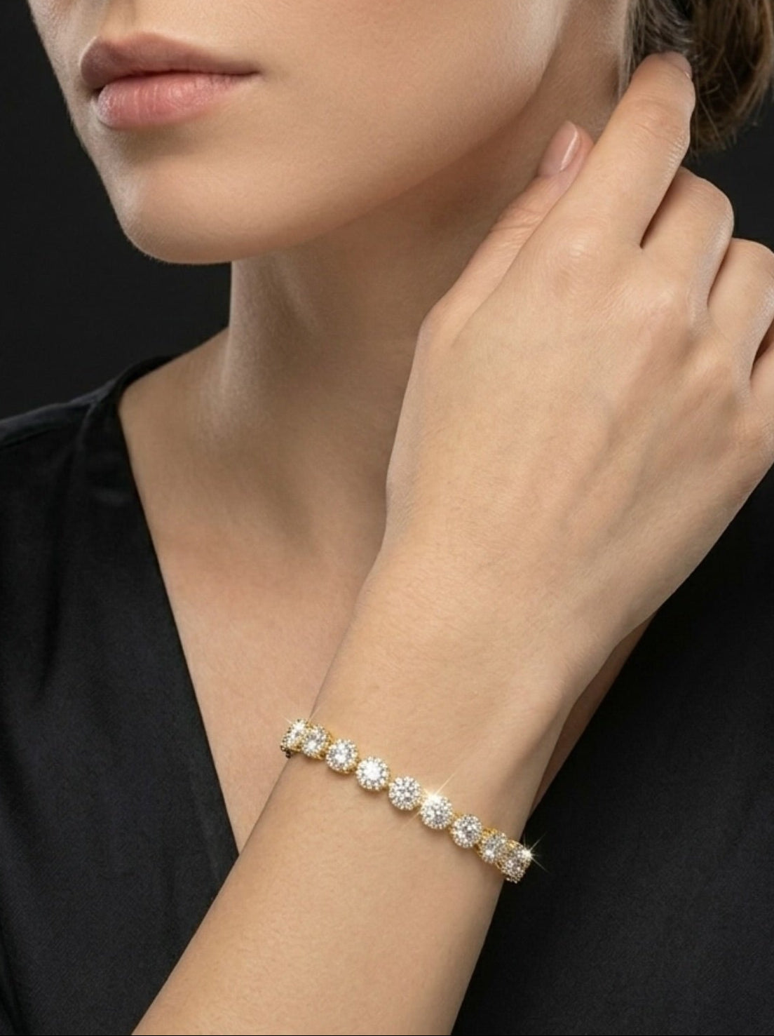 Woman wearing diamond earrings and bracelet against a black background