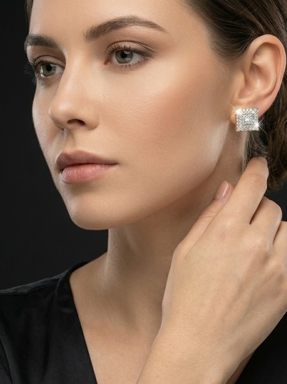 Woman wearing diamond earrings and bracelet against a black background